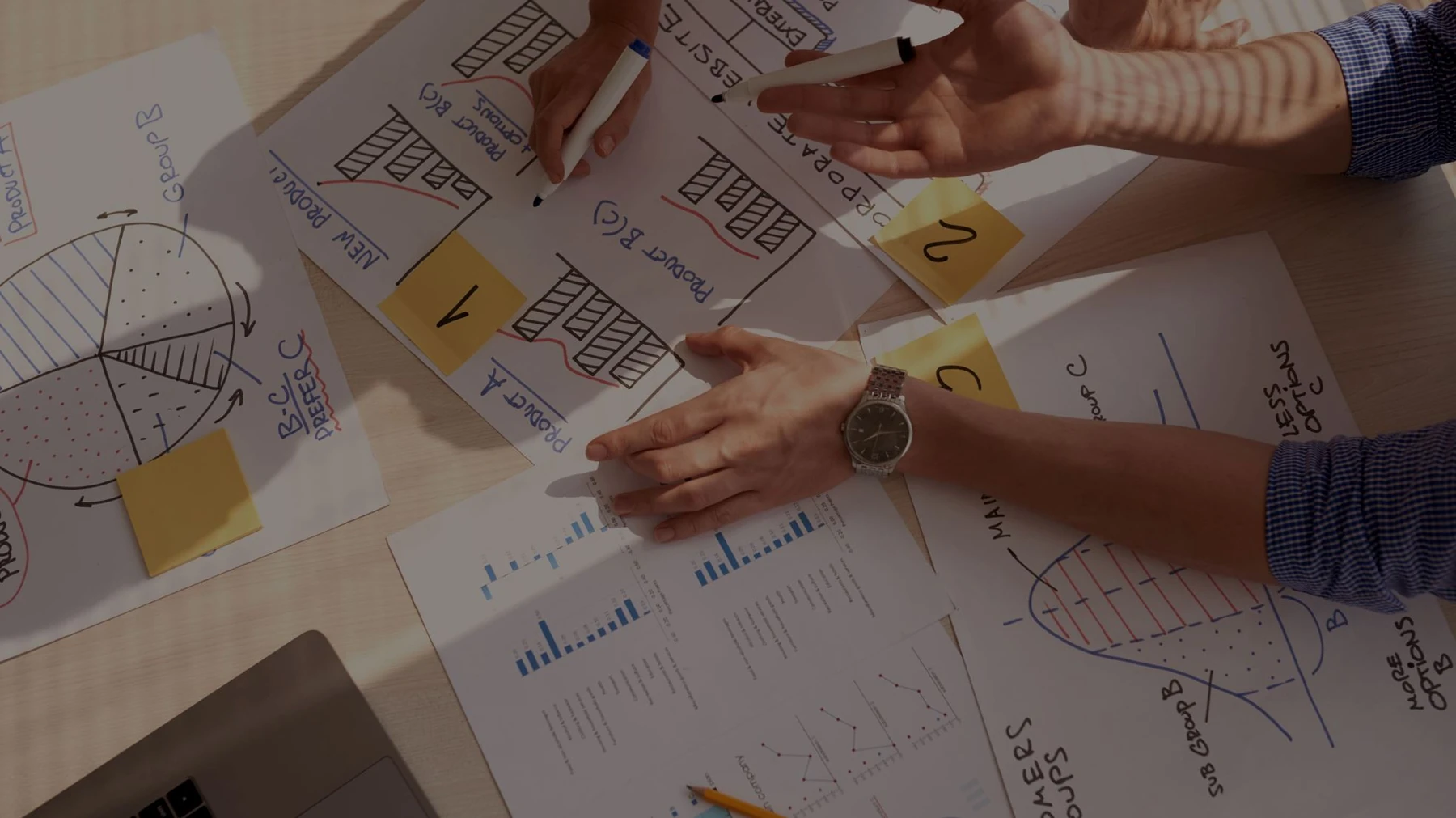 People review planning documents, sketches and charts around a table.