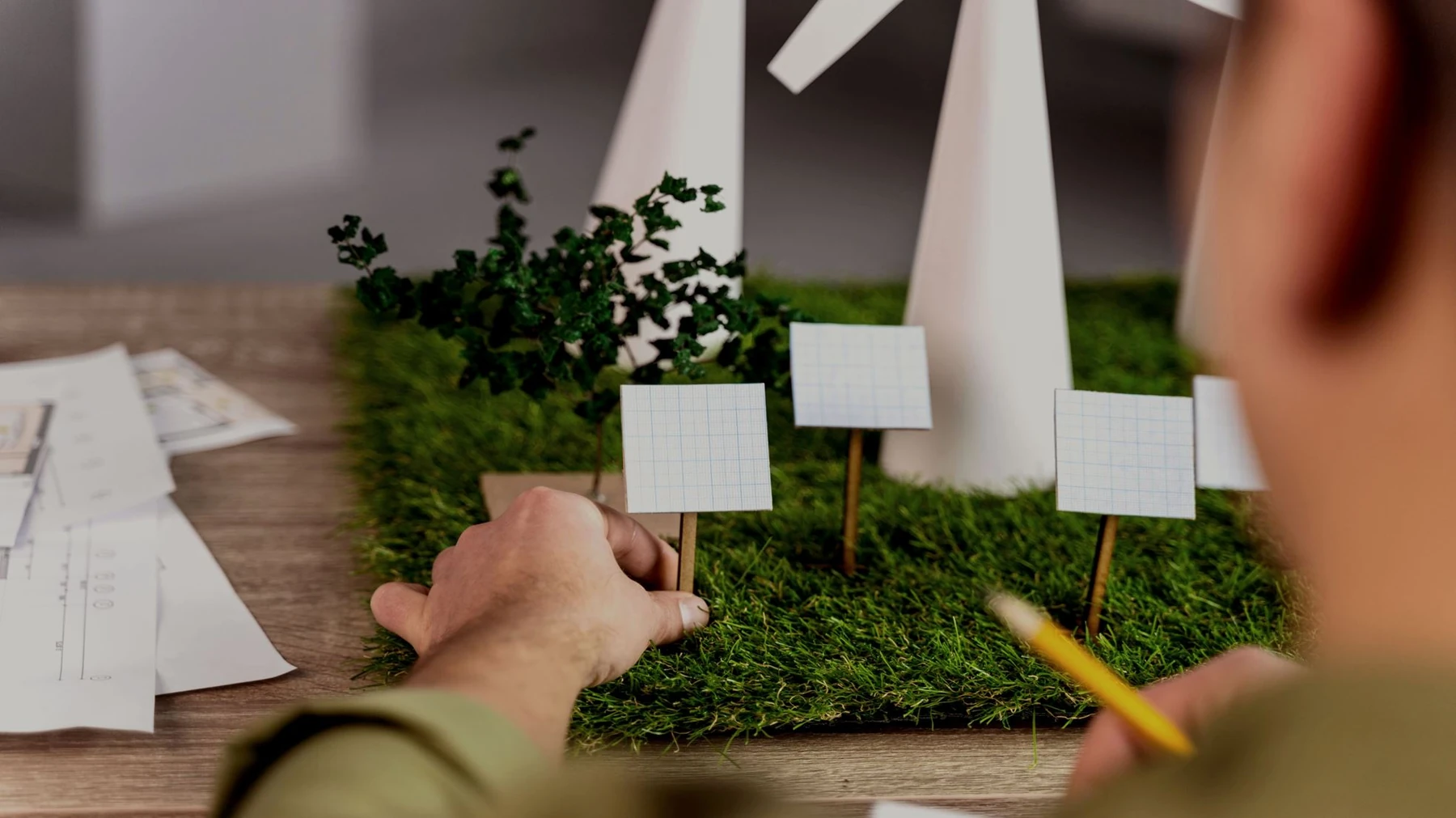 Hands review a small model of an energy and sustainability project.
